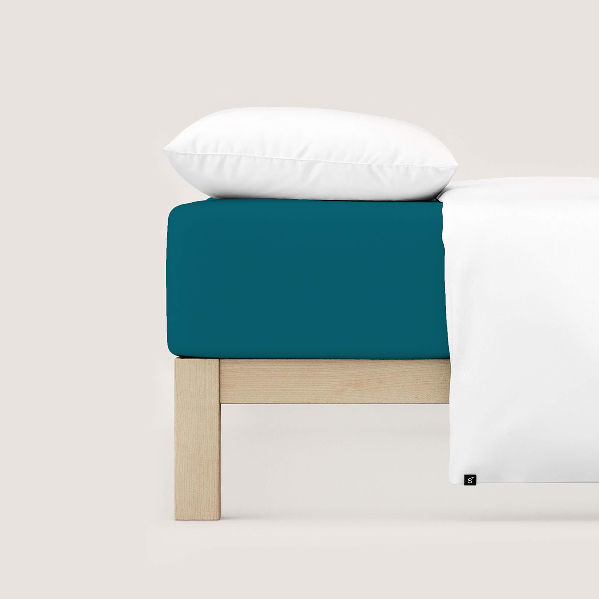 Spannbettlaken Casual von Schlafgut in Farbe petrol deep aus 100% Bio-Baumwolle auf Bett mit Kissen und Decke